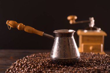 Teneke kutuda koyu kahverengi kahve çekirdekleri ve arka plan bulanık kahve değirmeni üstüne uzun ahşap saplı