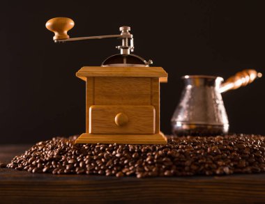 Ön görünümü bulanık küçük pot kahve çekirdekleri Höyük tepesinde saplı ve açık renkli ahşap kahve değirmeni