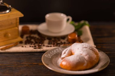 Pasta krema şeker ile tozunu tatlı bir kahve değirmeni ve Kupası arkasında bir tabakta servis