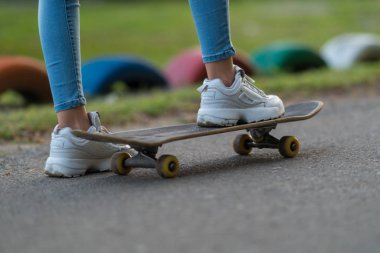 Spor ayakkabı lanmış bir yolda bir kaykay üzerinde duran genç bir kadın ayak düşük açılı görünüş
