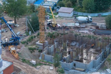 Ağır ekipman ve otomobillerde bitmemiş bir binanın etrafında bir ticari yapı sitesinin yüksek açılı görünüş