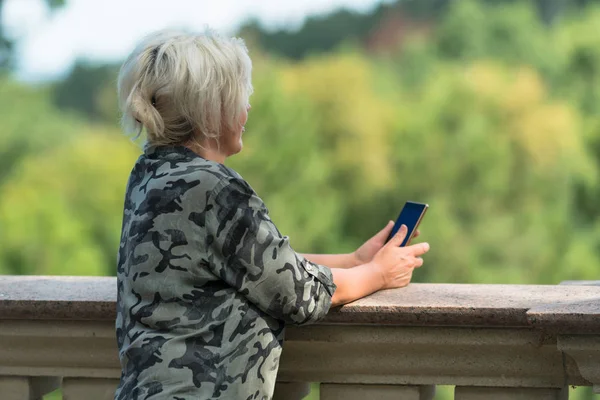Woman Standing Leaning Stone Parapet Holding Her Mobile Phone Staring — Stock Photo, Image