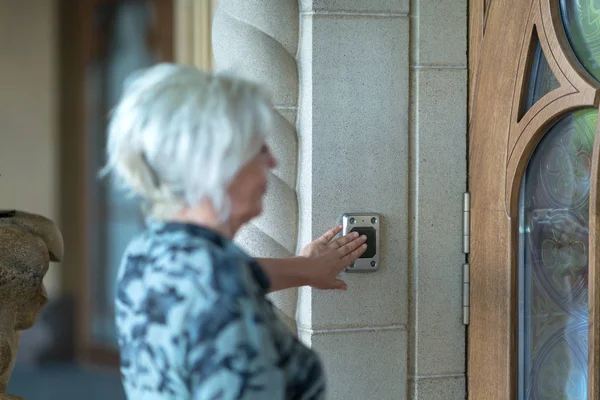Γυναίκα Λίγο Θολές Προσκηνίου Πατώντας Μαύρο Κουμπί Στον Τοίχο Πόρτα — Φωτογραφία Αρχείου