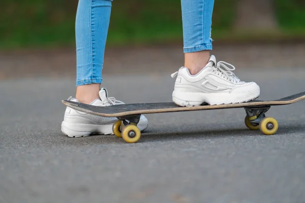 小女孩用脚滑板在一个小角度看她的运动鞋在沥青路 — 图库照片