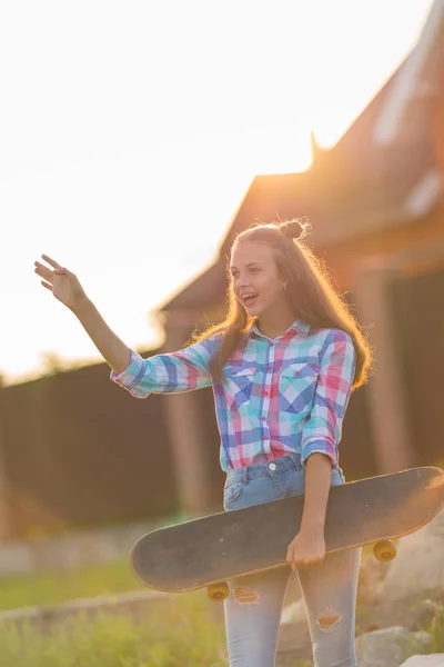 Aufgeregte Junge Frau Hält Ein Skateboard Der Hand Und Winkt — Stockfoto