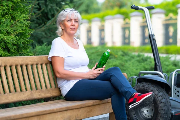 Mature Woman Holding Green Bottle While Sitting Wooden Bench Next — Stock Photo, Image