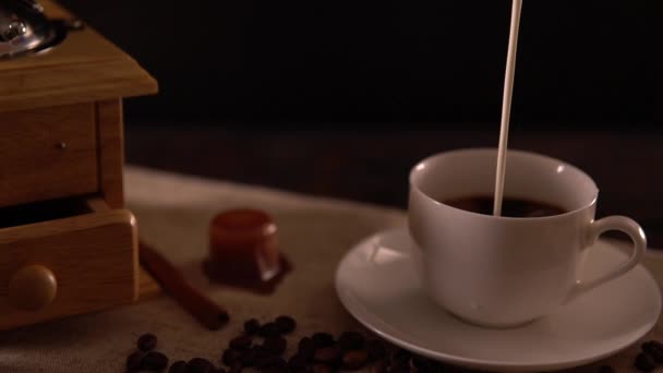 Gieten van verse melk in een kopje koffie — Stockvideo