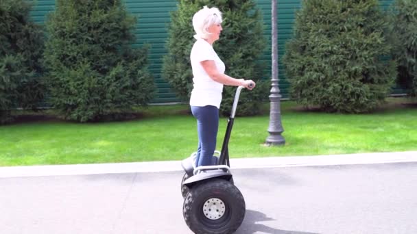 Femme chevauchant un transporteur personnel électrique le long d'une rue — Video