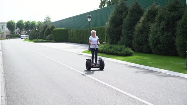 Mujer cabalgando más allá de la cámara en un transportador personal eléctrico — Vídeos de Stock