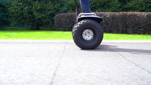 Mulher montando um transportador pessoal elétrico ao longo de uma estrada — Vídeo de Stock