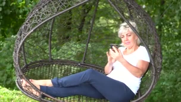 Blonďatá žena sedí v křesle mesh swing — Stock video