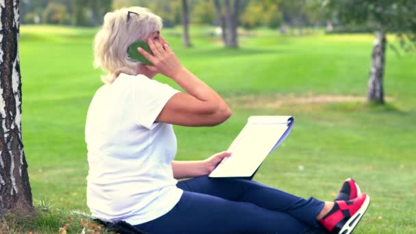 Vrouw op haar mobiel chatten terwijl ze zit te schetsen — Stockvideo