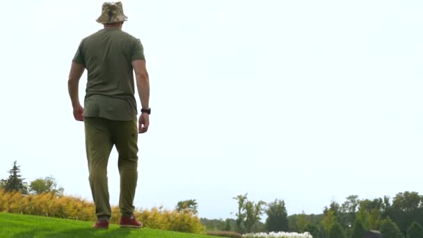 Bir parkta kısa otların arasında yürüyen adam — Stok video