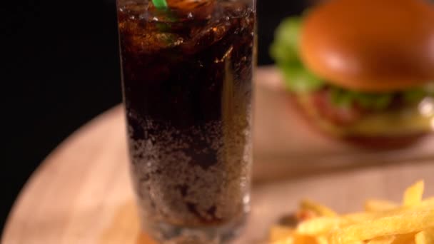 Tall glass of iced cola or soda with a burger — Stock Video