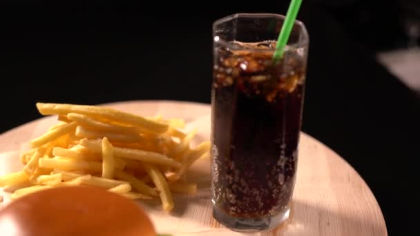 Cola in a tall glass with ice served with a burger — Stock Video