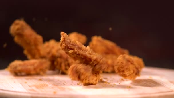 Stücke von gebratenen zerbröselten Hühnerflügeln fallen — Stockvideo