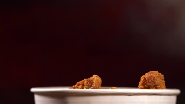 Pieces of crumbed fried chicken falling into a tub — Stock Video