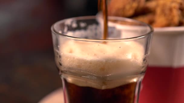 Pouring a glass of dark frothy beer — Stock Video