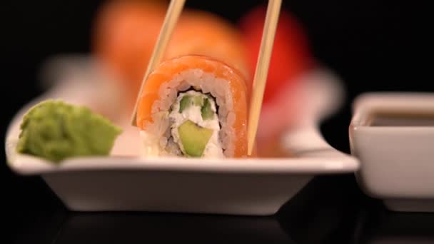 Rollo de sushi con wasabi sumergido en salsa de soja — Vídeo de stock