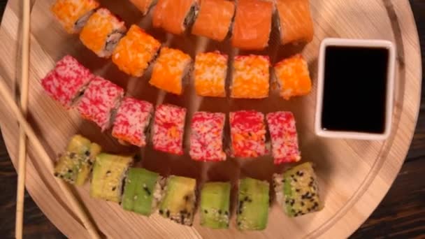 Junta de surtidos de rollos de sushi fresco y teléfono inteligente — Vídeo de stock