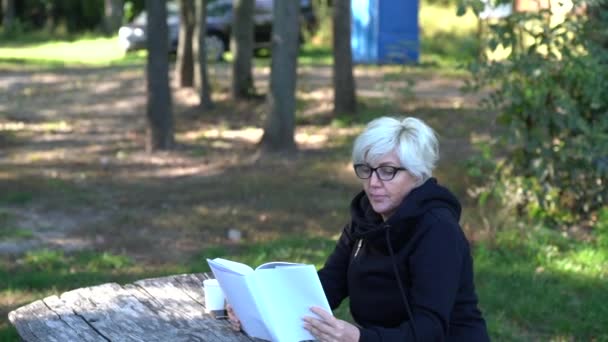 Μέσης ηλικίας γυναίκα διαβάζοντας ένα βιβλίο στο δάσος — Αρχείο Βίντεο