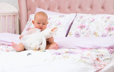 Yatakta bir kreş kopya alanı ile büyük bir peluş oyuncak ile oynarken küçük bebek kız