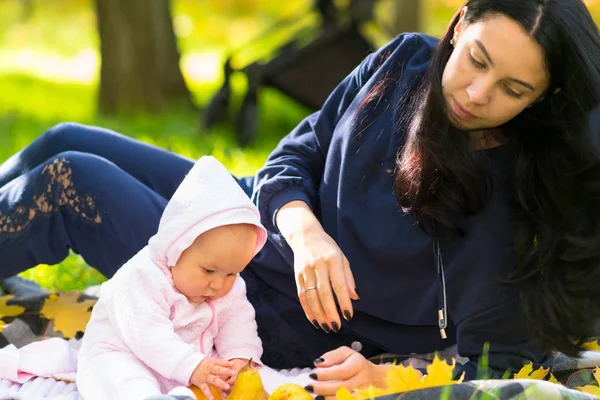 爱年轻的母亲看着她的小女儿玩一个成熟的苹果 因为他们一起在户外的地毯上放松秋天 — 图库照片