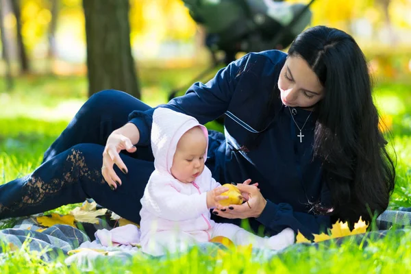 小女孩在户外的地毯上放松 和她有爱心的母亲在一起玩秋天的苹果 — 图库照片