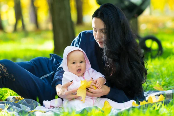 彼女は公園で毛布の上の愛情のある母親と Cuddles 葉笑って幸せな秋のカラフルな黄色で遊んで赤ちゃん女の子 — ストック写真