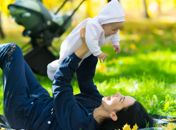 緑豊かな緑の芝生の公園で毛布の上にある彼女と彼女の幼い娘で遊んで笑って母 — ストック写真