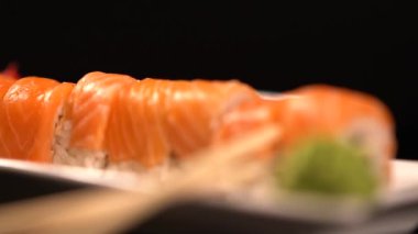 Soya sosu ve chopsticks bir dikdörtgen plaka bir garnitür ile servis taze somon suşi roll dilimlenmiş