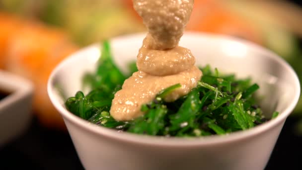 Соус с ложечкой над салатом из водорослей — стоковое видео