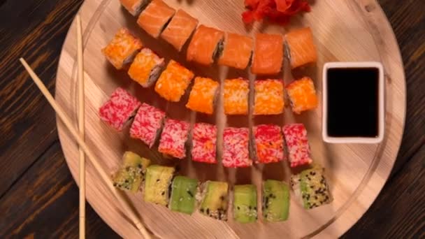Vista rotativa de sushi variado em uma placa de madeira — Vídeo de Stock