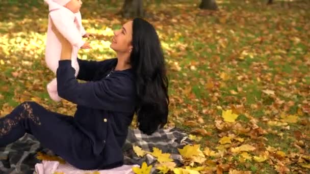 Jeune femme en noir jouer avec bébé dans le parc — Video