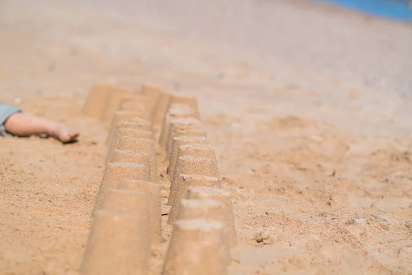 コピー スペースを持つビューを間近に水の端で砂浜に小さな砂の城の行 — ストック写真