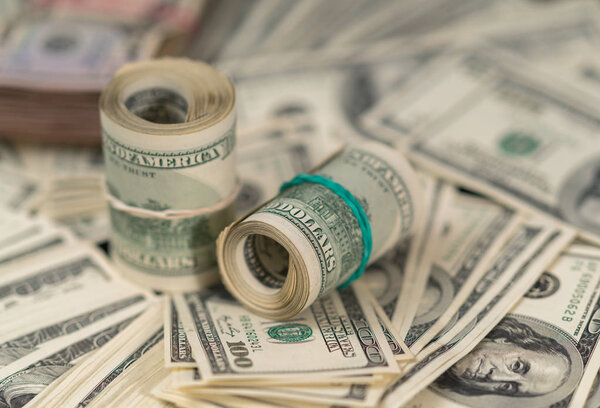 Ролики 100-долларовых купюр на грудах денег в избирательном фокусе концептуального полного фона кадра
