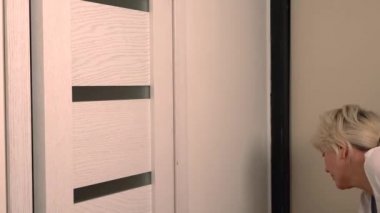 Sarışın kadın boya fırçası ile bir duvara dokunarak