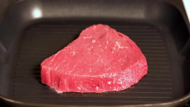 Шеф-повар кладет сырой говяжий стейк в горячую сковородку — стоковое видео