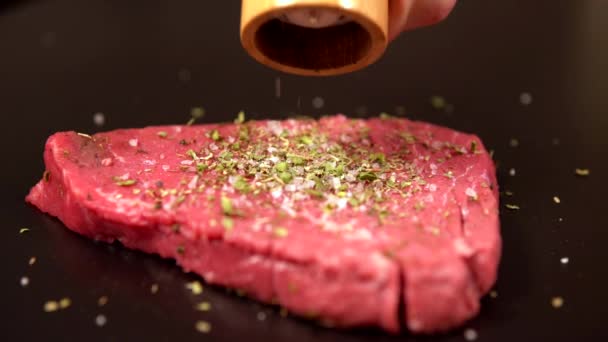 Chef moliendo pimienta en un filete de carne cruda — Vídeo de stock