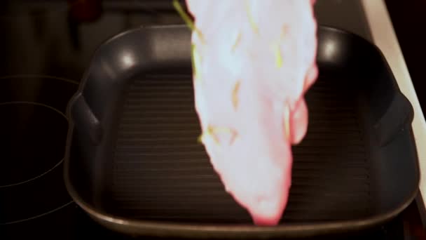 Женщина кладет сырую куриную грудку в сковородку — стоковое видео