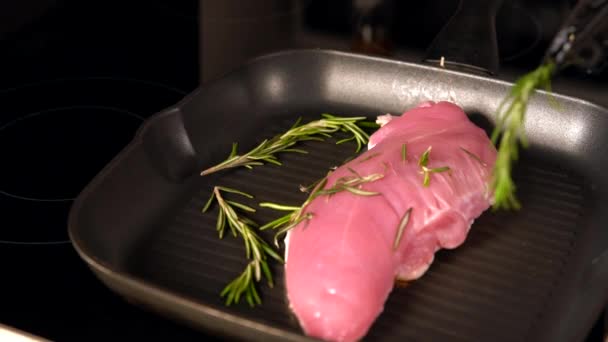 Повар кладет веточки свежего розмарина на курицу — стоковое видео