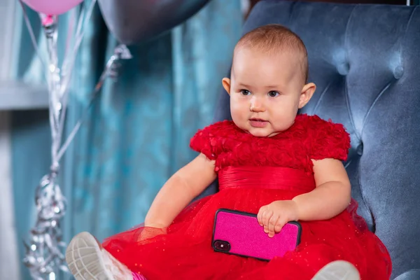 Schattig kind meisje in een rode jurk met smartphone — Stockfoto