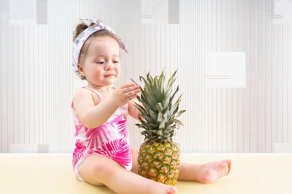 Bir ananas ile oynamaya meraklı küçük bebek kız — Stok fotoğraf