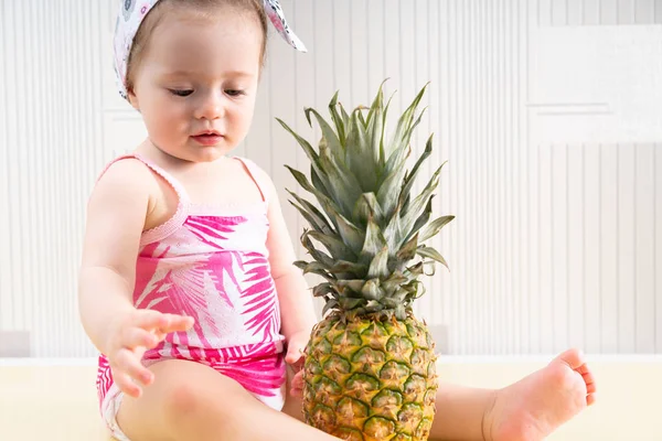 Jonge babymeisje op zoek naar grote ananas — Stockfoto