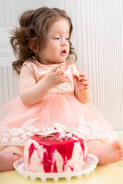 Linda niña en vestido rosa comiendo pastel dulce — Foto de Stock