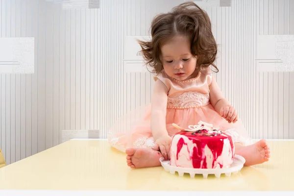 Menina bonito com bolo vermelho e branco na mesa — Fotografia de Stock