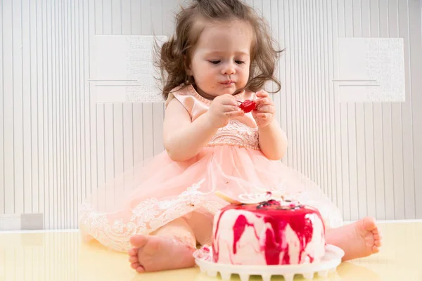 Niña en vestido rosa comiendo un pastel — Foto de Stock