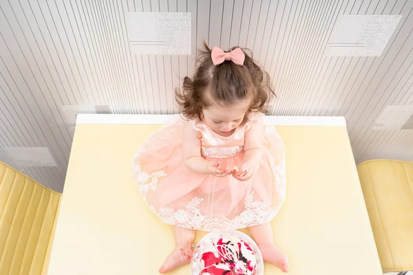 Meisje van de baby met strik taart, eten van bovenaf — Stockfoto