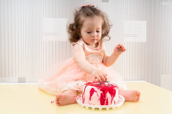 Hübsches kleines Mädchen streckt sich nach einem Kuchen aus — Stockfoto