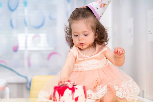 Junges Mädchen im rosa Kleid isst Geburtstagstorte — Stockfoto